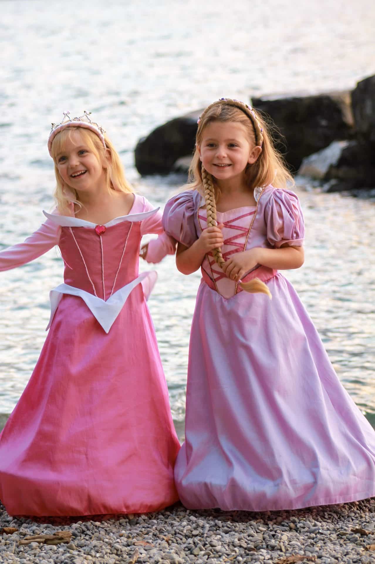 Twee meisjes aan zee, waarvan het rechter meisje de paarse Rapunzel jurk met pofmouwen en lange rok draagt.