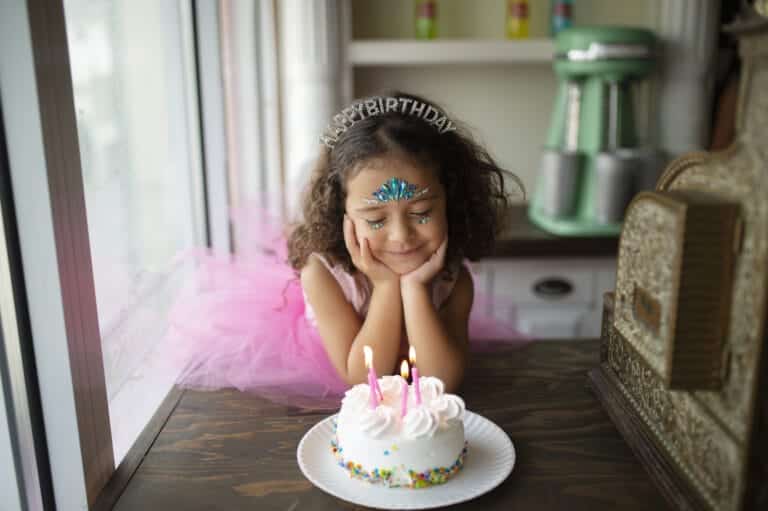 Meisje draagt de zilverkleurige Happy Birthday haarband tijdens haar verjaardagsfeest met taart en kaarsjes