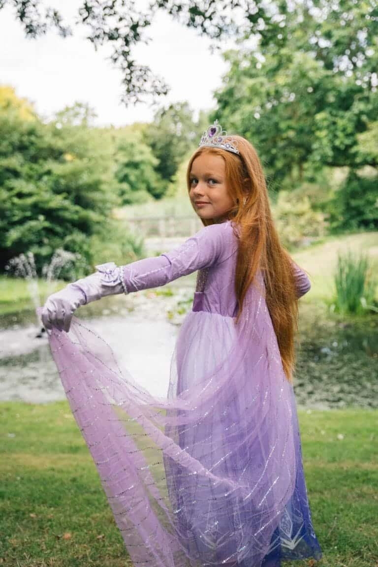 Meisje draagt een paarse frozen elsa jurk van Het Betere Merk met tiara en handschoenen, terwijl ze de rok optilt