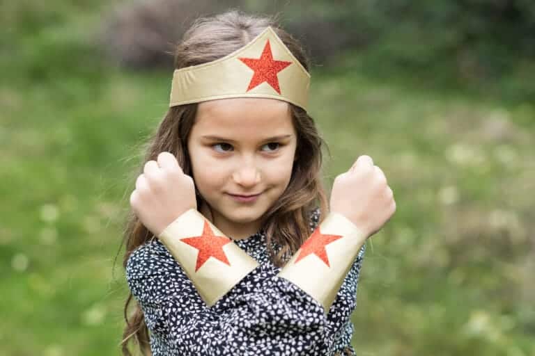 Meisje draagt de Superhero Girl-hoofdband en bijpassende polsbandjes met rode glittersterren in een kruispose