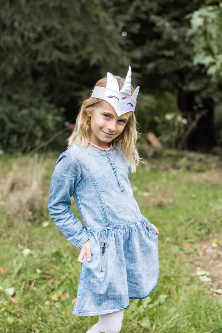 Meisje draagt de Eenhoorn hoofdband met witte unicorn hoorn en oortjes in een groene tuin