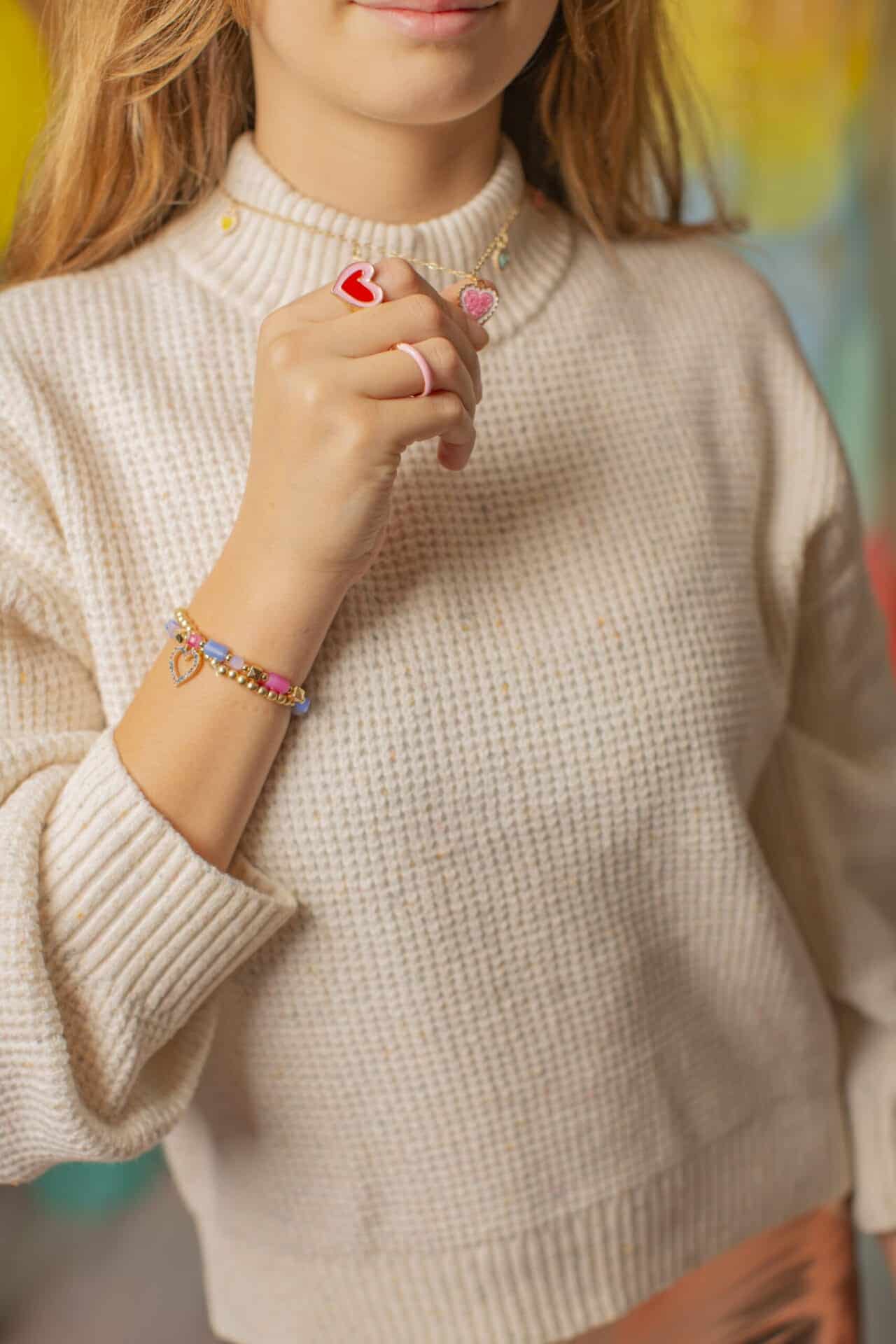 Meisje draagt de kinderringen – 2 stuks met een rode en roze hartjesring aan haar hand
