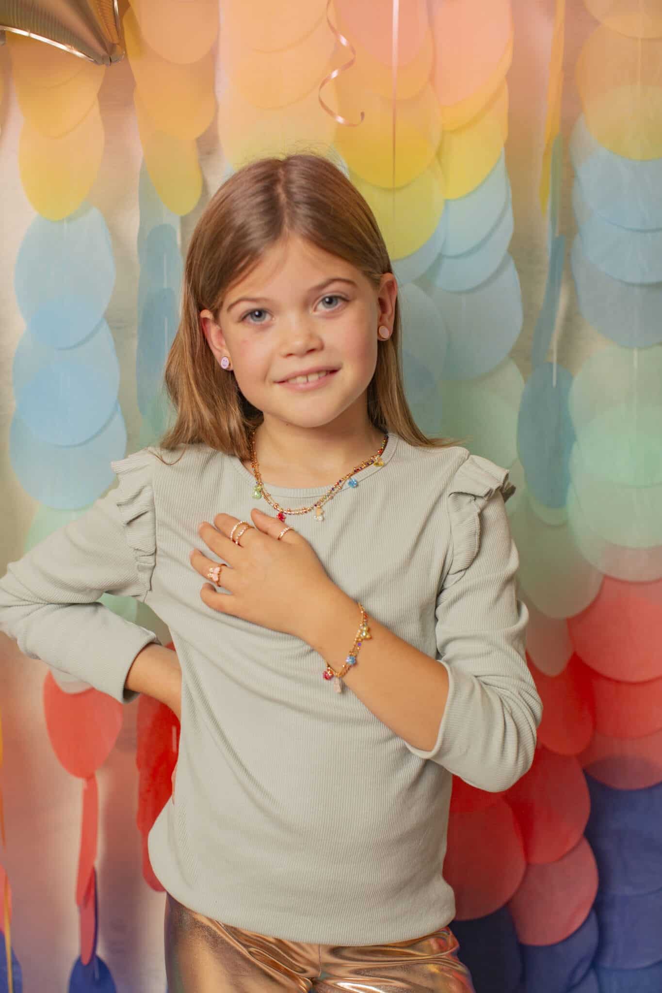 Meisje draagt de Great Pretenders Gummybeertje ketting met kleurrijke hangers en een bijpassende armband