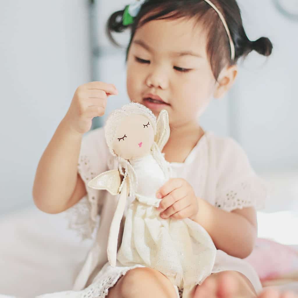 Kind houdt de Great Pretenders Knuffel Charlotte the Fairy van 30 cm vast, met witte jurk en vleugels.