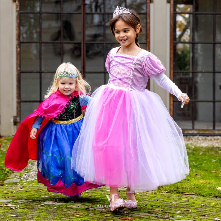 Een meisje draagt de roze en lila prinsessenjurk Rapunzel met tiara en toverstaf.