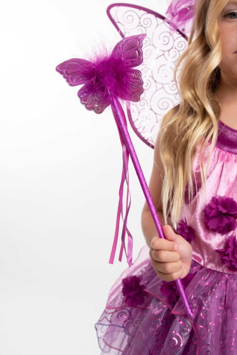 Meisje houdt de paarse toverstaf met vlinder en linten uit de Feeën en prinsessen-set vast