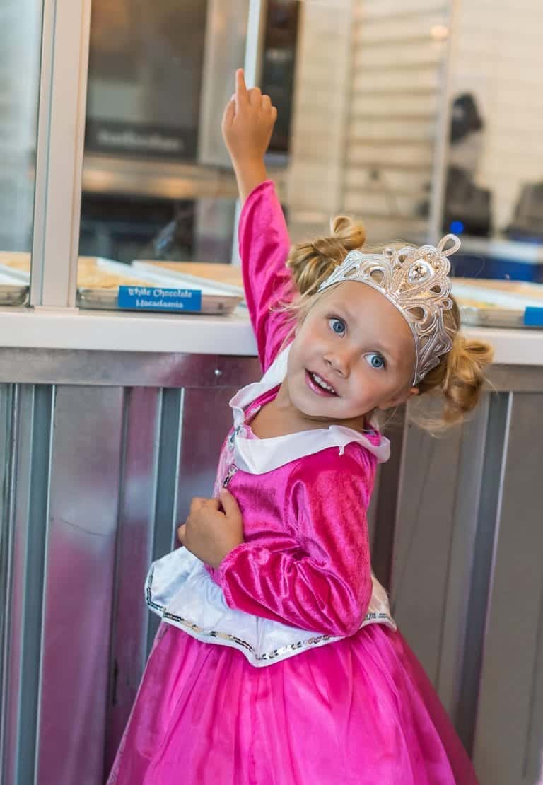 Meisje draagt een roze Little Adventures Doornroosje prinsessenjurk met witte kraag, zilveren details en een tiara.