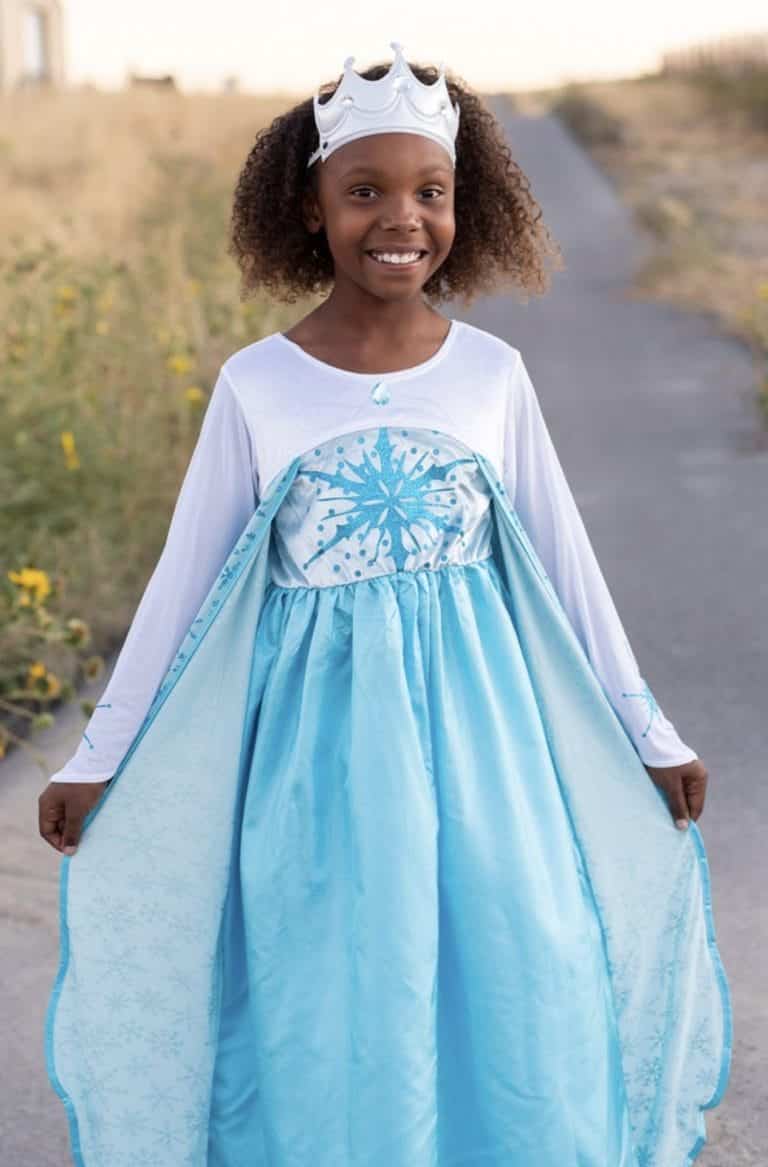 Meisje draagt een blauwe elsa jurk met grote sneeuwvlok op het lijfje, wijde doorschijnende sleep en witte kroon.