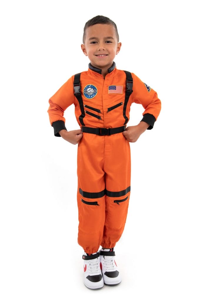 Vooraanzicht van een jongen in de oranje Astronaut verkleedset tegen een witte achtergrond, met zijn handen in de zij.