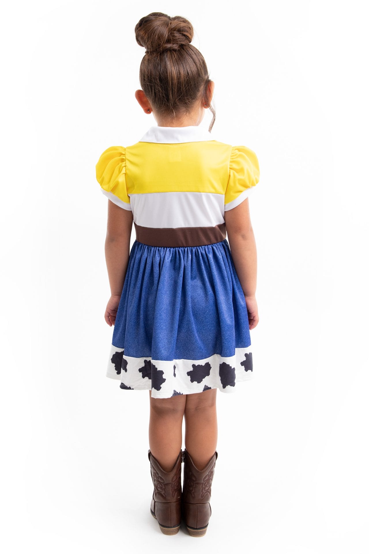 Achteraanzicht van een meisje in de toy story cowgirl jurk van Little Adventures, met geel-wit lijfje, bruine tailleband en blauwe rok.