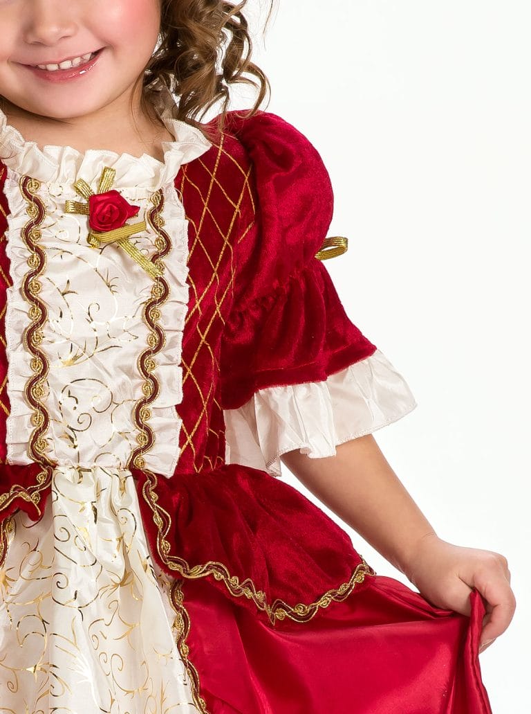 Detail van een rode prinsessenjurk van fluweel, gedragen door een kind, met witte ruches, gouden biezen en een rode roos.