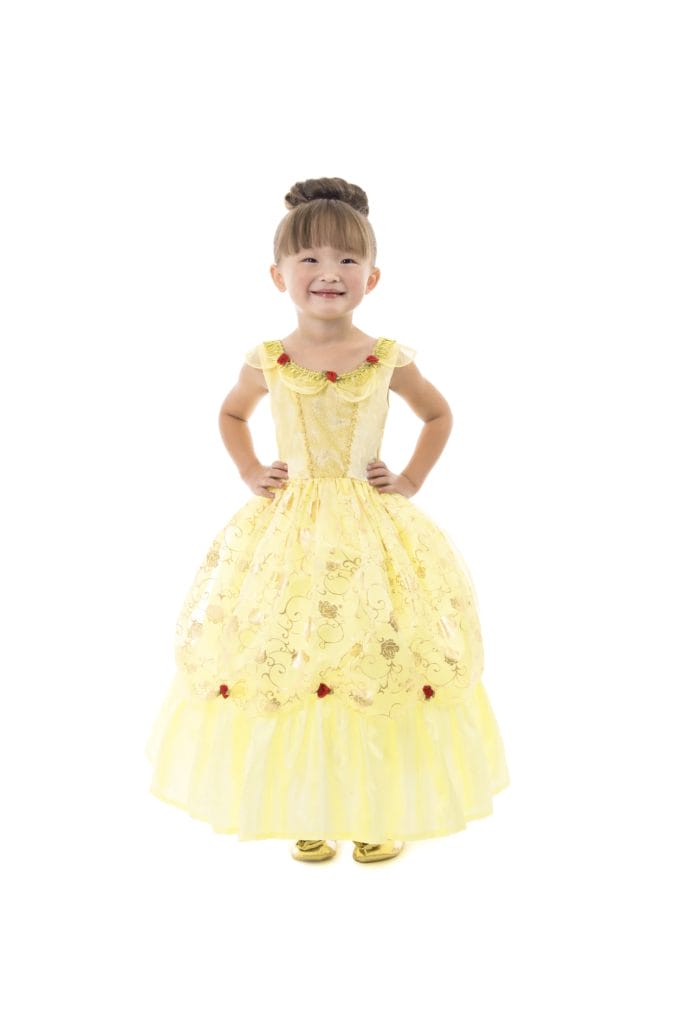 Meisje draagt een gele Belle prinsessenjurk met rode roosjes en gouden motieven, met haar handen in de zij.