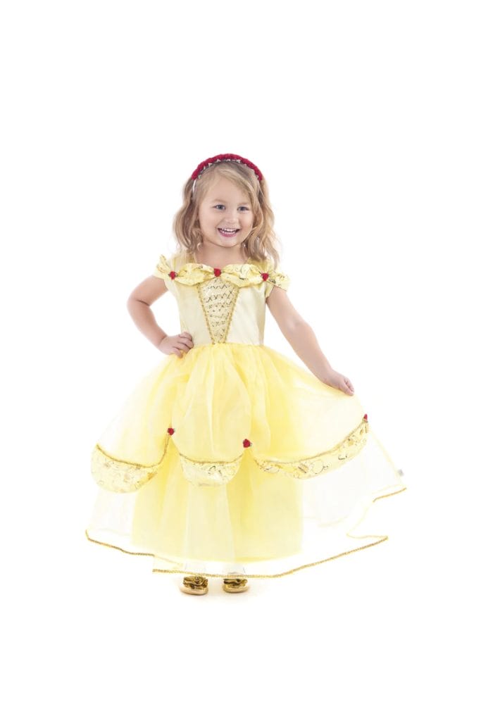 Meisje draagt een gele Belle jurk van Little Adventures met gouden sierbies, rode roosjes en een wijde organzarok.