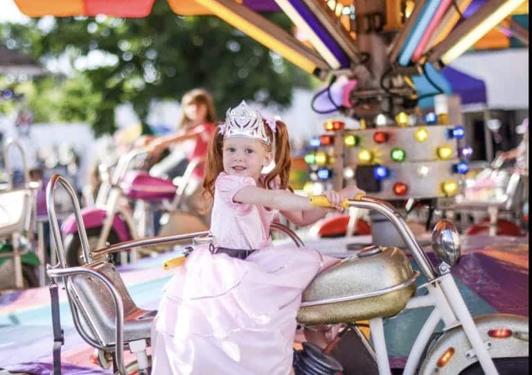 Meisje draagt de zilveren kroon van Little Adventures tijdens een ritje in een roze prinsessenjurk.