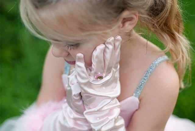 Meisje draagt roze prinsessenhandschoenen met ruches en een versiering bij een roze jurk