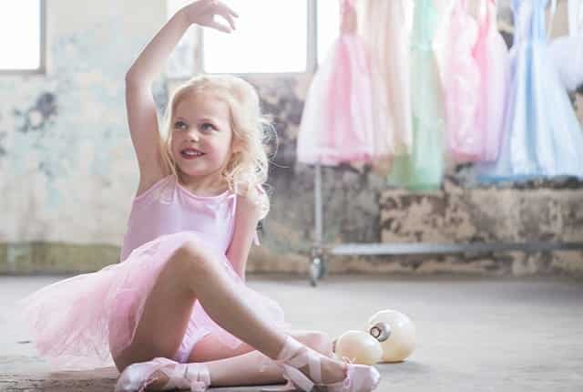 Meisje draagt een roze ballerina jurk kind met tutu en balletschoenen, terwijl ze een danshouding aanneemt