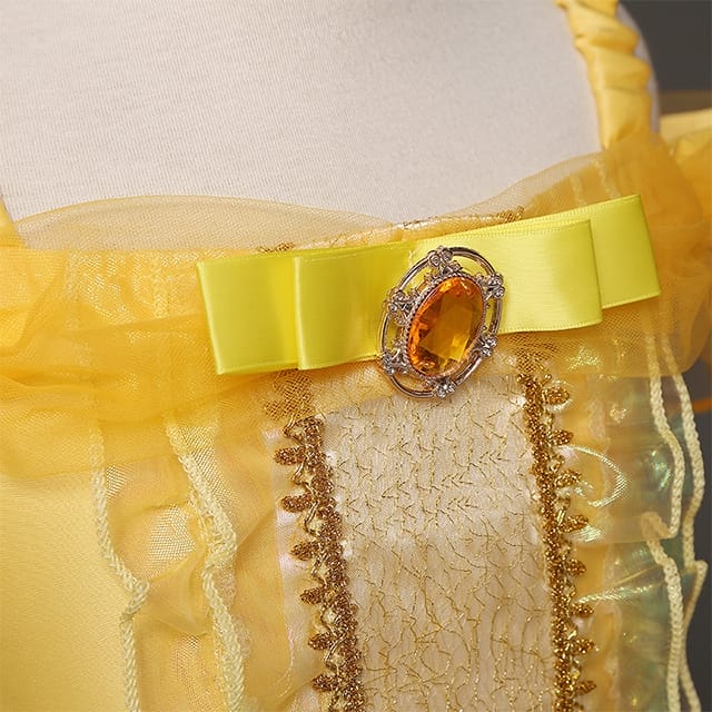 Detail van de gele prinsessenjurk belle met een brede satijnen tailleband en ovale oranje edelsteen op het lijfje.