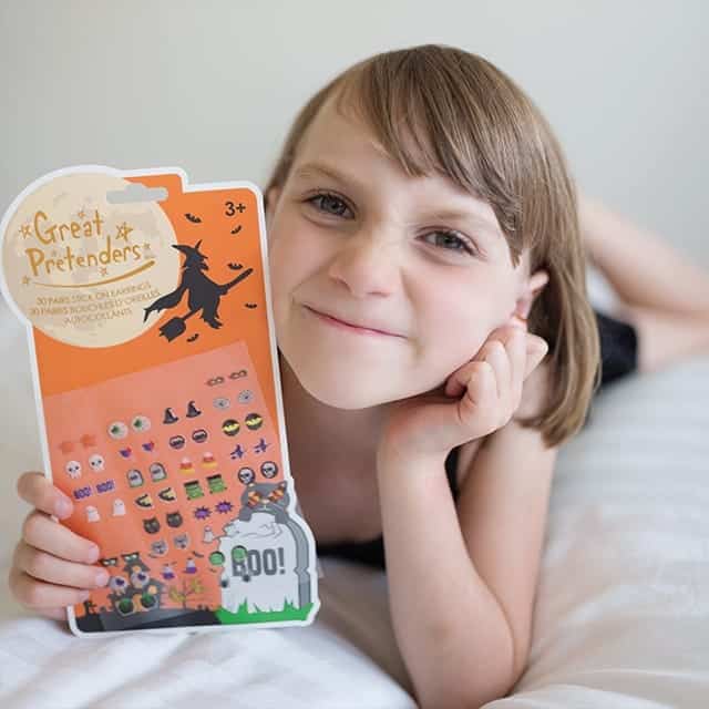 Meisje toont een vel met 30 paar kleurrijke plak oorbelletjes voor Halloween, met spookjes, vleermuizen en pompoenen