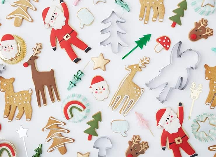 Twee zilveren kerst koekjes uitstekers in de vorm van een kerstboom en rendier tussen versierde kerstkoekjes