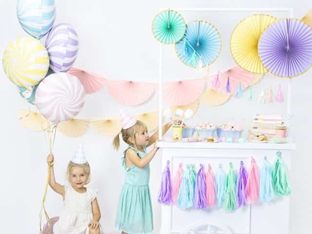 Mintgroene candy folieballon in een kleurrijke pastelversiering tijdens een kinderfeestje met twee meisjes