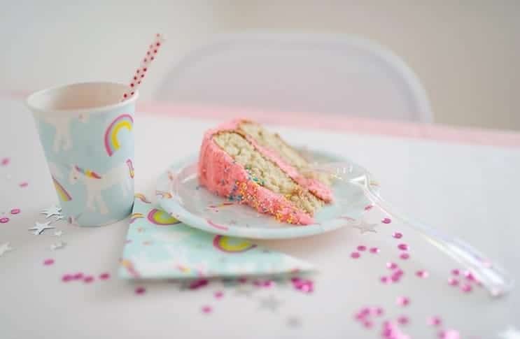 Unicorn accessoires: lichtblauw unicorn partybordje met een stuk roze taart, naast een bijpassende beker en servet.