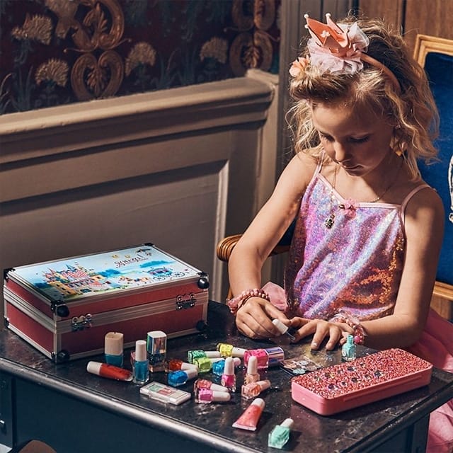 Meisje gebruikt de souza nagellak uit de nagellak cadeauset, met meerdere kleuren en accessoires op tafel.