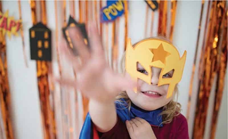Superhelden thema feest met een kind met gouden masker voor de feestslinger Gebouwen met zwarte panden