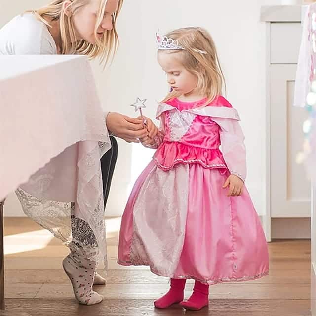 Meisje draagt een roze Doornroosje classic jurk met glanzende rok en zilveren tiara, terwijl ze een sterstaf vasthoudt.