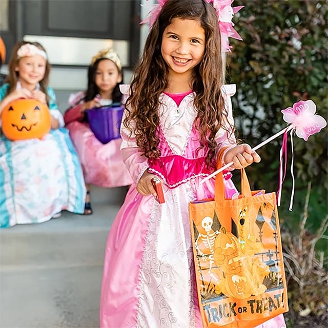 Meisje draagt een roze-witte Doornroosje jurk met zilveren versiering en houdt een Halloween-tas en roze toverstaf vast.
