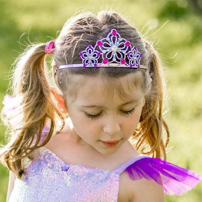 Meisje draagt de lila en zilveren prinsessenkroon met paarse en blauwe kralen, close-up buiten in het groen