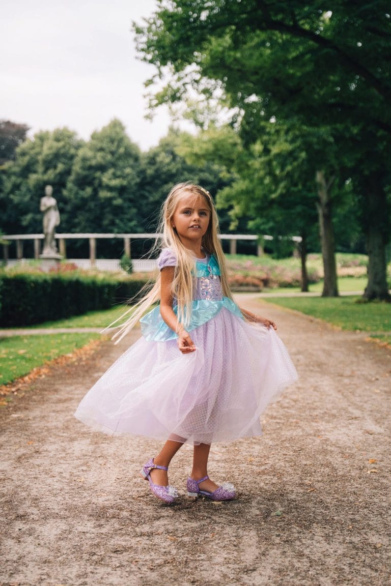 Meisje draagt een paarse zeemeerminjurk met turquoise lijfje en tule rok in een park.