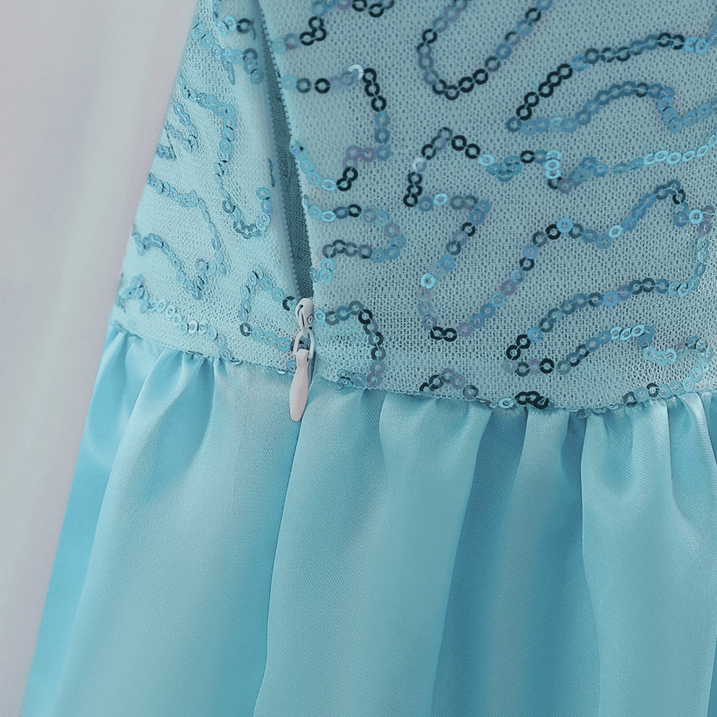 Detail van de blauwe Frozen jurk met glanzende paillettenstof, tule rok en zichtbare rits