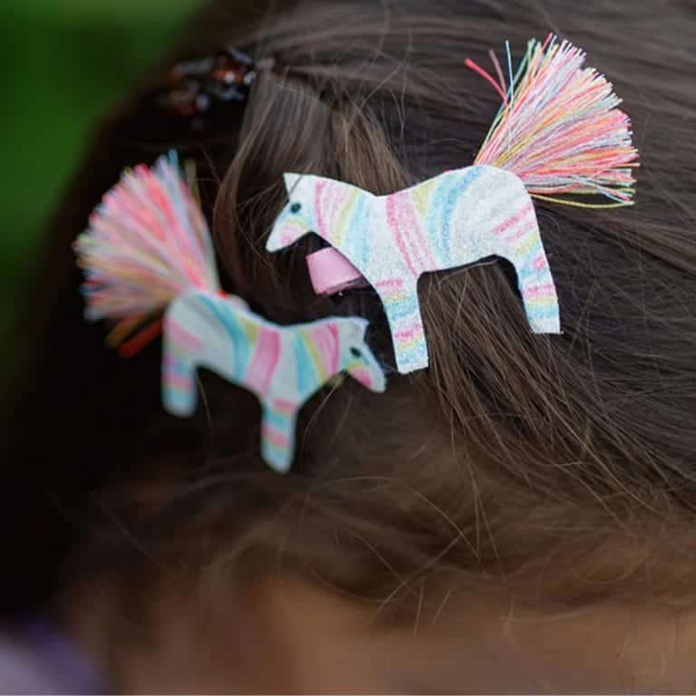 Kleurrijke haarclips met paardjes en franjes in het bruine haar van een kind