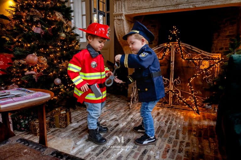 Twee jongens dragen beroepen verkleedkleding: een Great Pretenders politiepak en een rood brandweerkostuum.