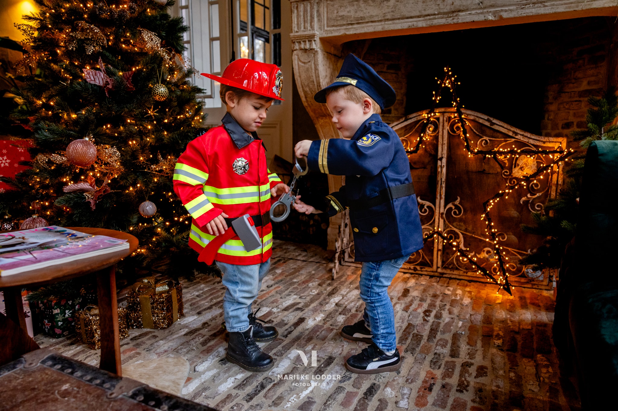 Twee jongens dragen beroepen verkleedkleding: een Great Pretenders politiepak en een rood brandweerkostuum.