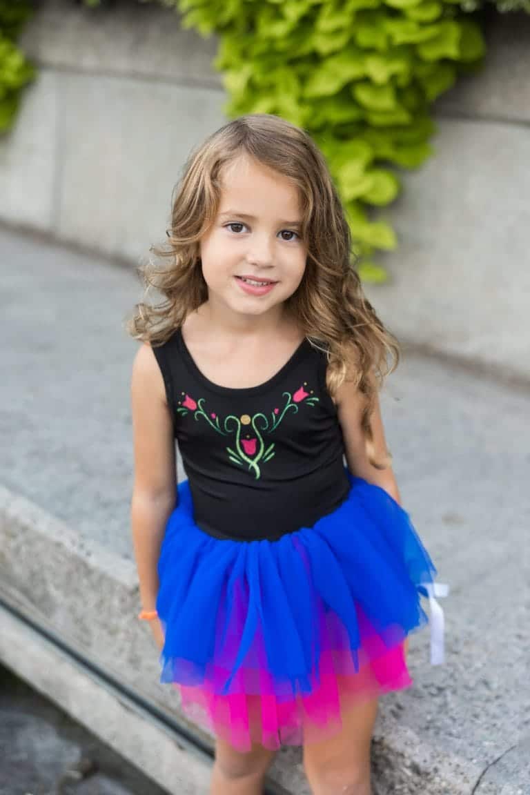 Meisje draagt een Anna tutu jurk met zwarte top, geborduurde bloemen en een blauwe en roze tule rok