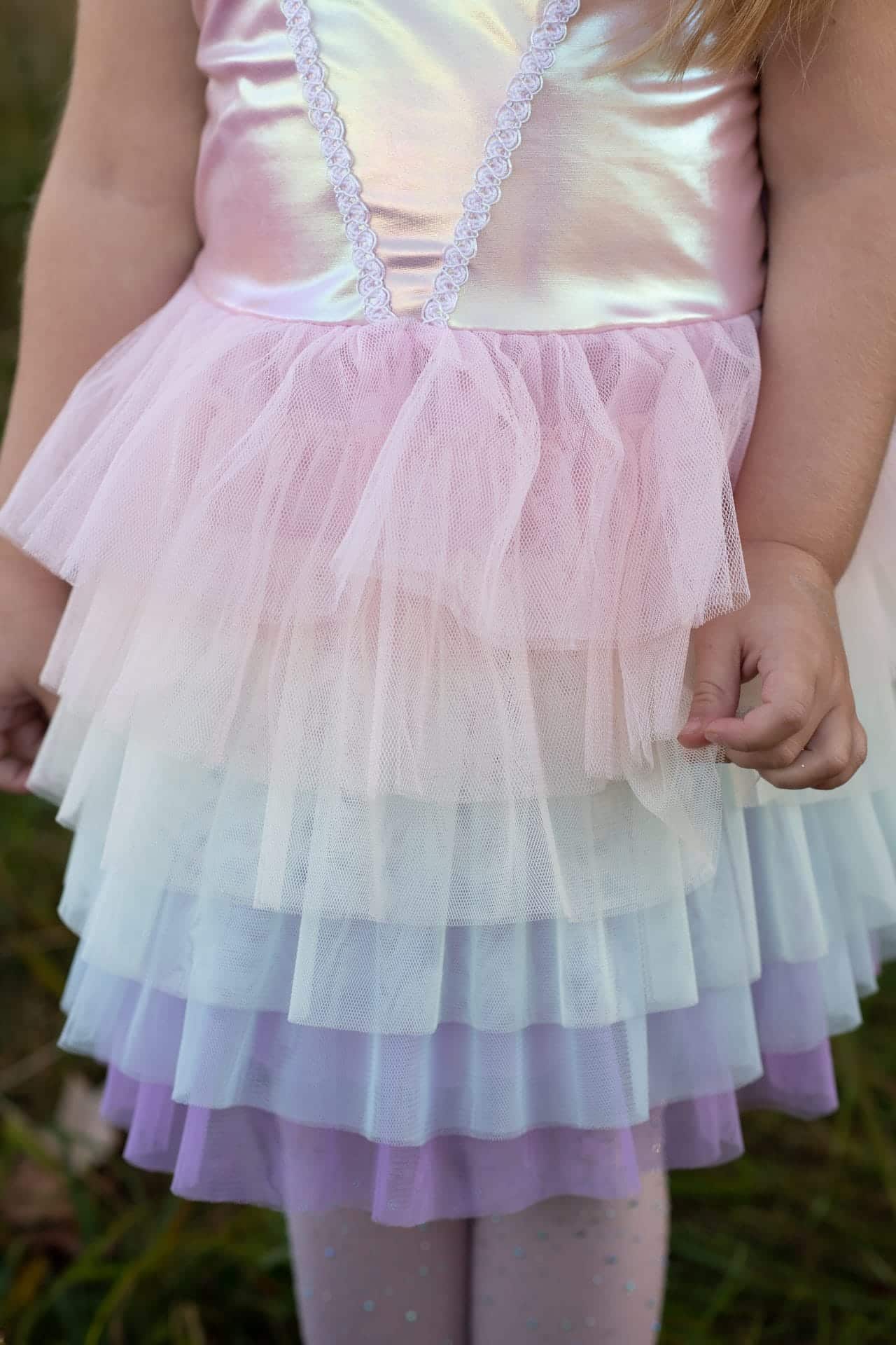 Close-up van de great pretenders tutu op een meisje, met glanzend roze lijfje en lagen pastelgekleurde tule