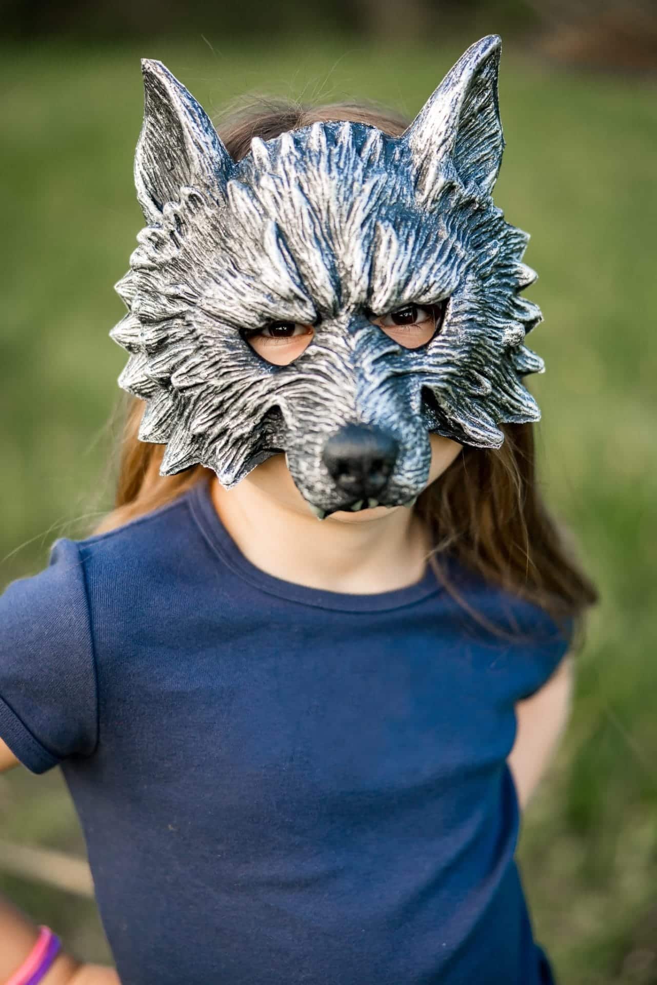 Meisje draagt een grijs weerwolf masker met puntige oren en een grote zwarte neus
