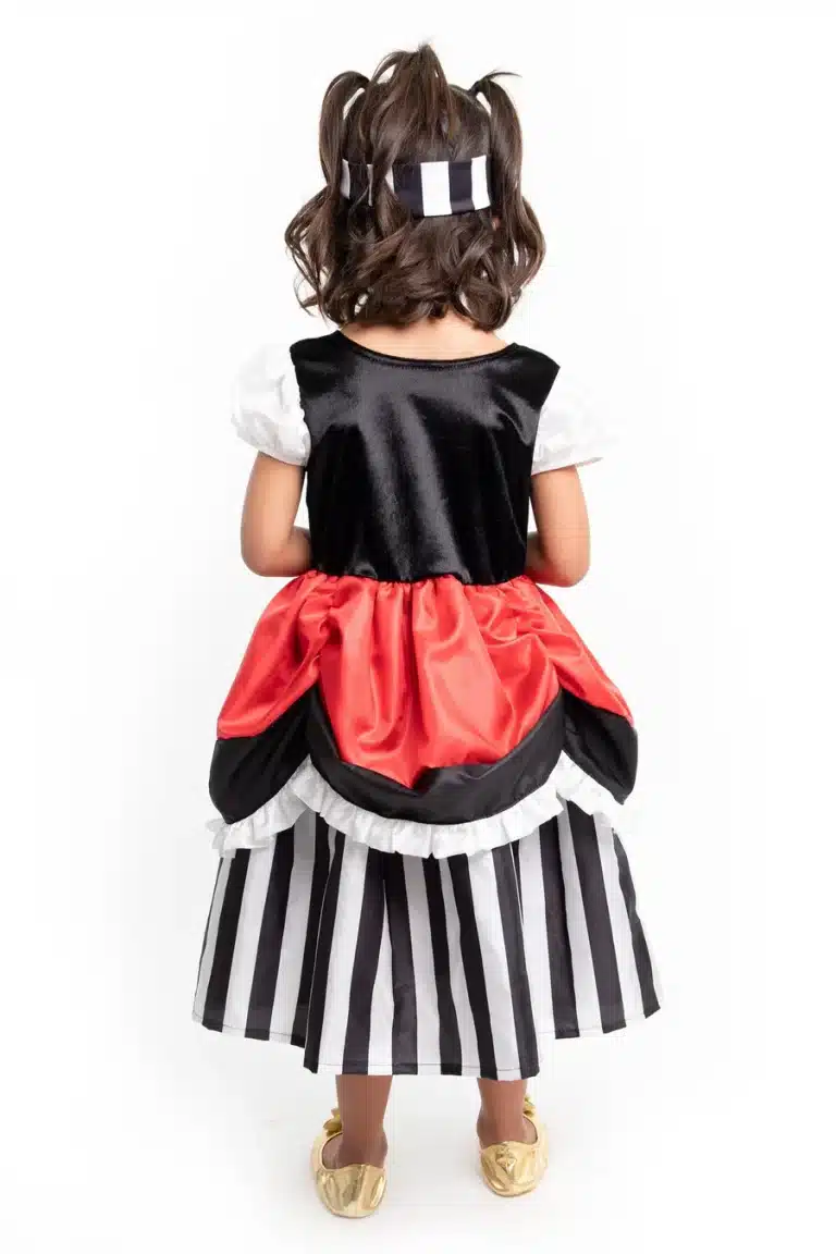 Achteraanzicht van een kind in de zwart-witte piratenprinsessenjurk met rode rok en bijpassende hoofdband.