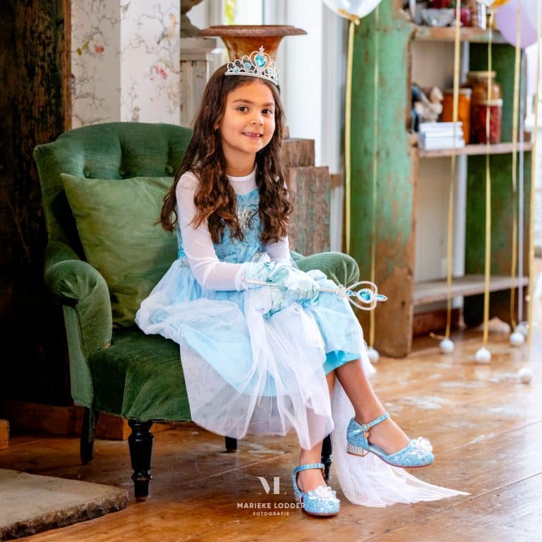 Meisje draagt een lichtblauwe Elsa jurk uit het voordeelpakket met tiara, handschoenen, toverstaf en glinsterende schoenen.