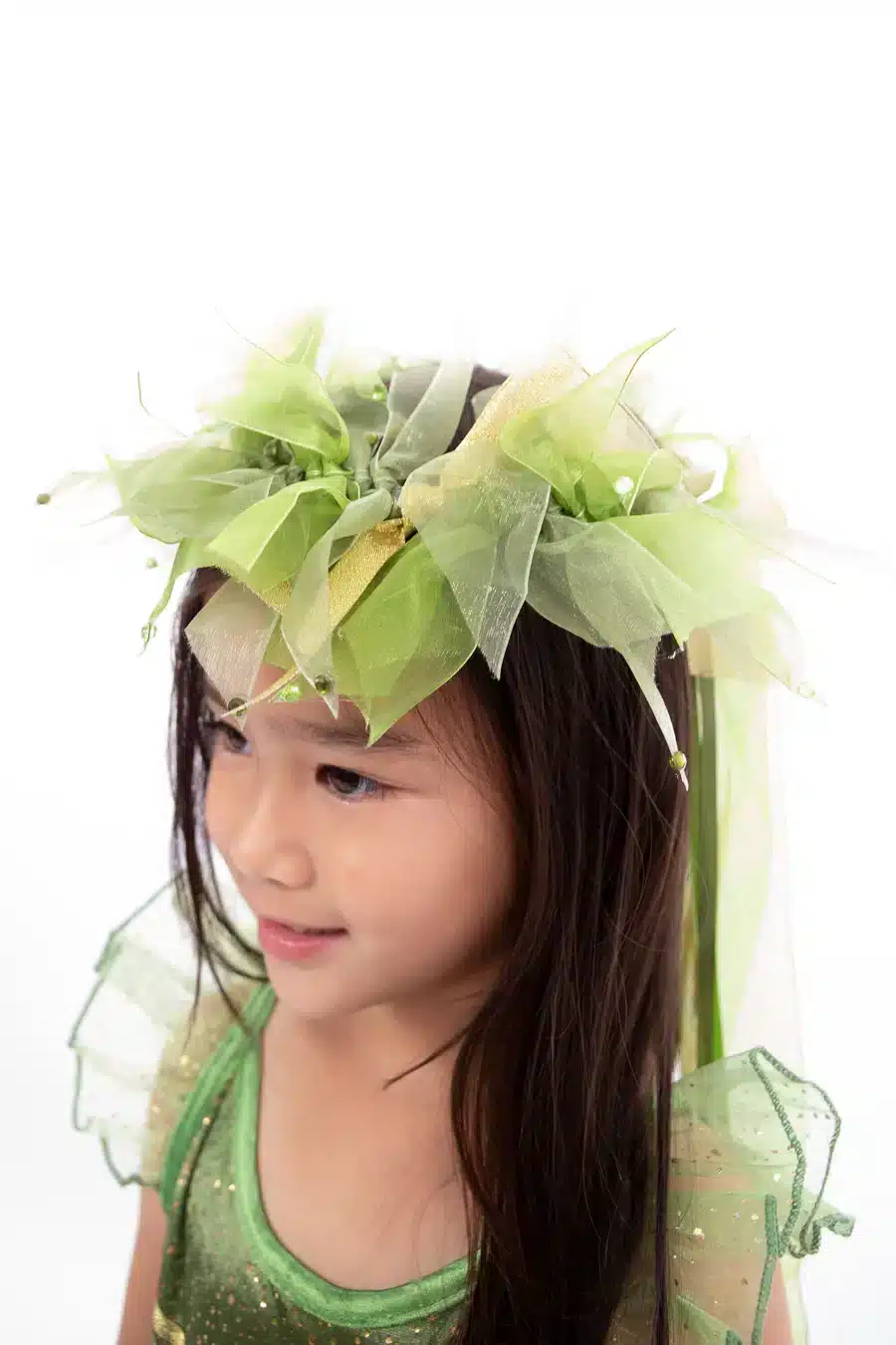 Meisje draagt de groene bloemenkrans van het Tinkerbell kostuum kind van Little Adventures, met linten en blaadjes