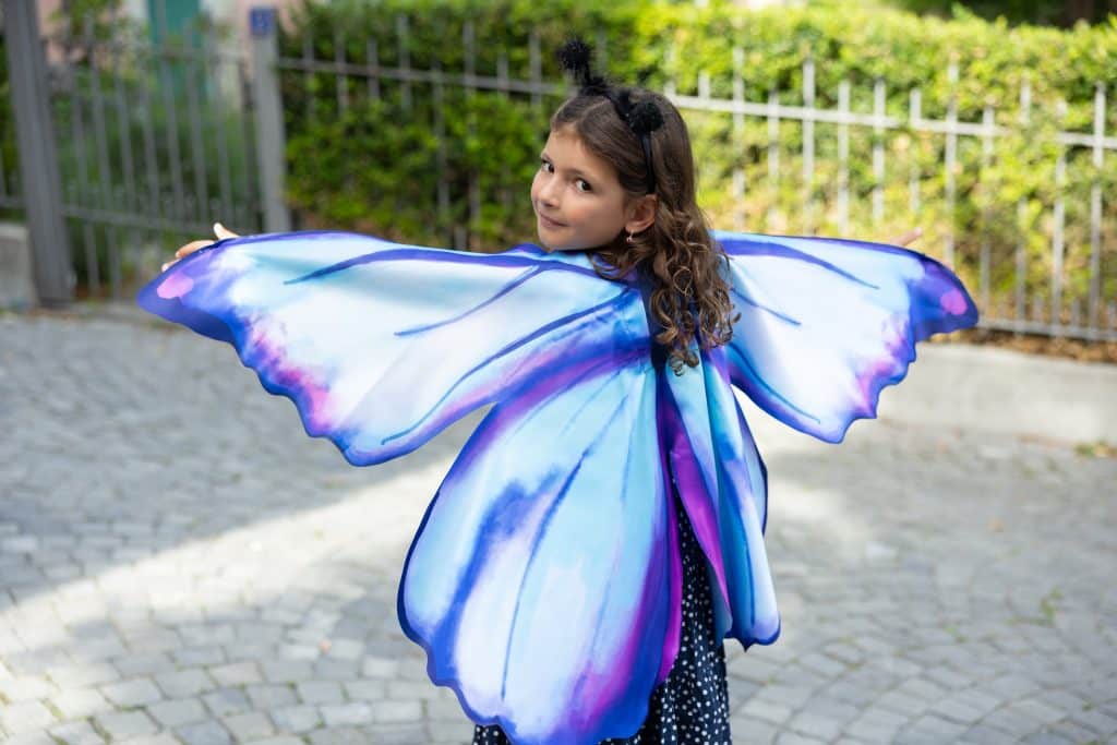 Meisje draagt paarse en blauwe vlindervleugels van de Mythical Butterfly Soft Wings Set, uitgespreid op haar rug