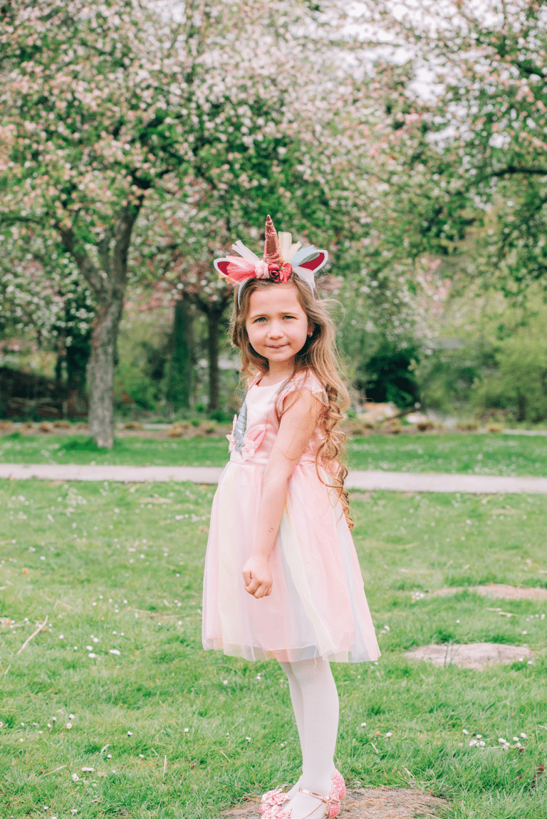 Meisje draagt een roze unicorn jurkje met tule rok en eenhoornhaarband in het park, van Het Betere Merk.