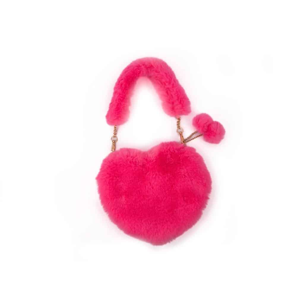 Roze fluffy hartvormig handtasje met pluche hengsel, gouden kettinkje en pluizige sleutelhanger op een witte achtergrond