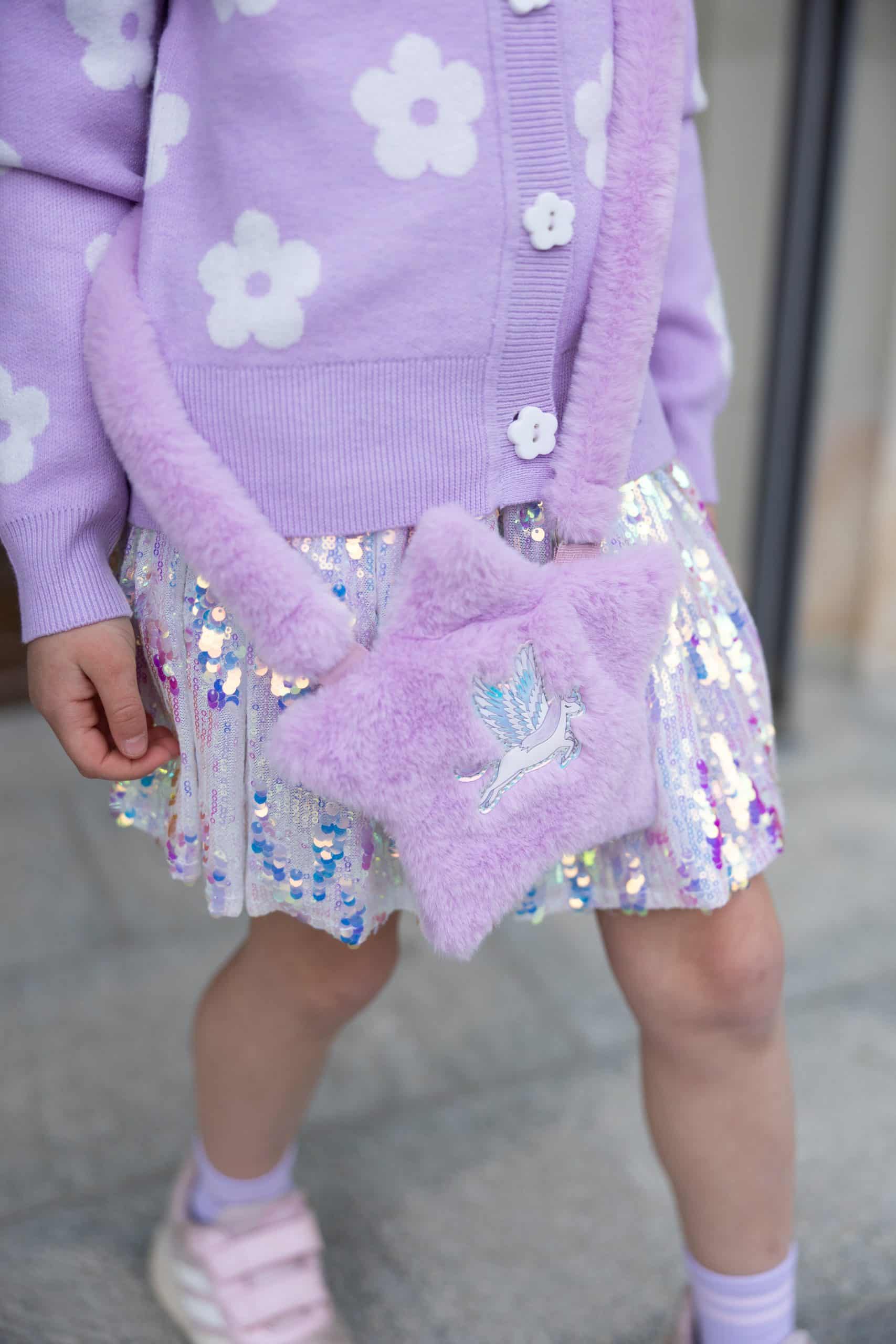 Kind draagt de pailletten rok zilver met glanzende veelkleurige pailletten en een paarse tas met zwaan