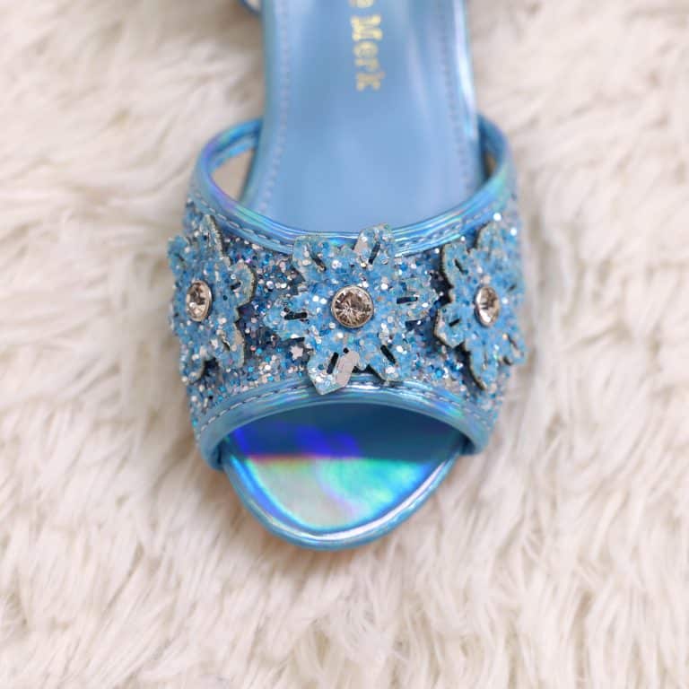 Close-up van een blauw prinsessenschoentje met glitters, bloemen en zilverkleurige steentjes op de band