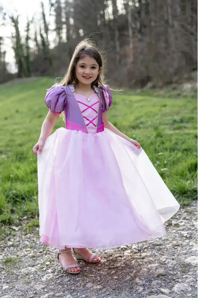 Volledige Rapunzel prinsessenjurk in paars en roze, gedragen door een meisje dat de wijde rok optilt op een bospad.