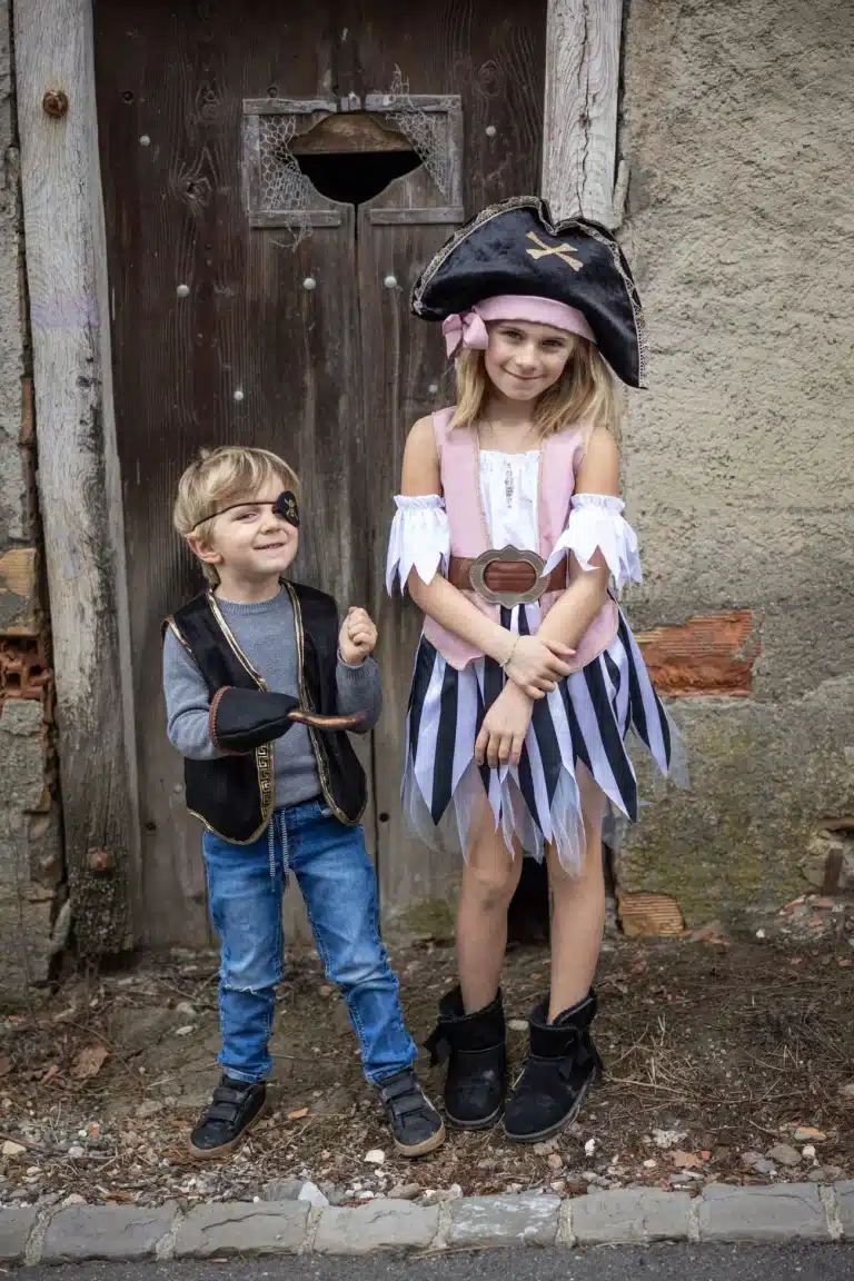 Meisje draagt de piratenjurk met roze lijfje, gestreepte rok, witte mouwen en zwarte piratenhoed naast een jongen