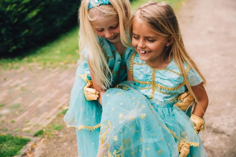 Twee meisjes dragen een turquoise jasmine jurk met gouden versiering en een rok met sterretjes