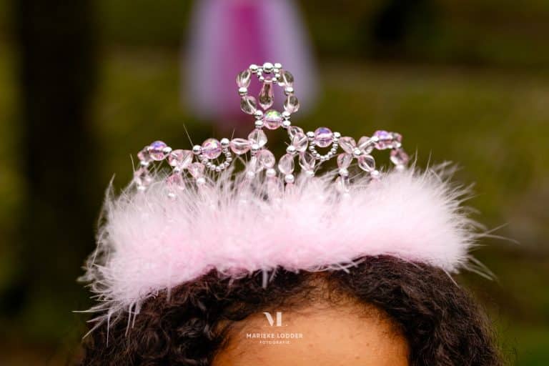 Roze prinsessenkroon met zachte veren en glanzende kraaltjes op het hoofd van een kind